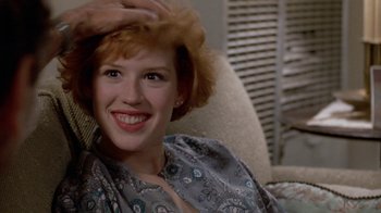 Movie still from “Pretty in Pink” (1986), directed by Howard Deutch – A woman sitting in a chair smiling for the camera; Close Up shot, Over the shoulder angle