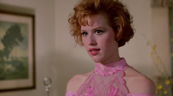 Movie still from “Pretty in Pink” (1986), directed by Howard Deutch – A woman in a pink dress is posing for a picture; Close Up shot, Over the shoulder angle