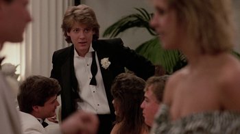 Movie still from “Pretty in Pink” (1986), directed by Howard Deutch – A man in a tuxedo standing in front of a group of people; Medium shot, Over the shoulder angle