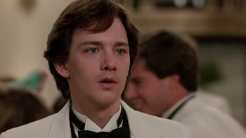 Movie still from “Pretty in Pink” (1986), directed by Howard Deutch – A young man in a white suit and a black bow tie; Close Up shot, Low angle