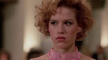 Movie still from “Pretty in Pink” (1986), directed by Howard Deutch – A person with curly hair wearing a pink dress; Close Up shot, Over the shoulder angle