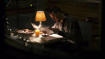Movie still from “Pride and Glory” (2008), directed by Gavin O'Connor – A man sitting at a table reading a magazine; Medium shot, High angle