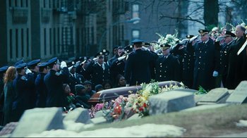 Movie still from “Pride and Glory” (2008), directed by Gavin O'Connor – A group of men in uniform saluting a casket in a cemetery; Wide shot, High angle