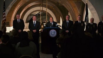 Movie still from “Pride and Glory” (2008), directed by Gavin O'Connor – A group of men in suits and ties standing in front of a podium; Wide shot, Low angle