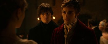 Movie still from “Pride and Prejudice and Zombies” (2016), directed by Burr Steers – Two young men standing next to each other in a dark room; Medium shot, Over the shoulder angle