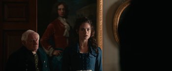 Movie still from “Pride and Prejudice and Zombies” (2016), directed by Burr Steers – A woman standing in front of a painting in front of a mirror; Medium shot, Over the shoulder angle
