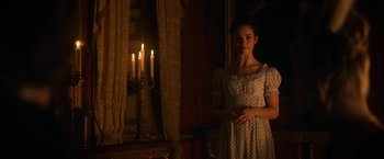 Movie still from “Pride and Prejudice and Zombies” (2016), directed by Burr Steers – A woman standing in front of candles in a dimly - lit room; Medium shot, Over the shoulder angle