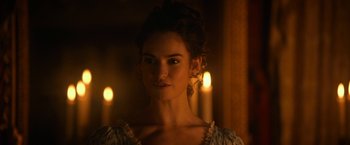 Movie still from “Pride and Prejudice and Zombies” (2016), directed by Burr Steers – A beautiful young lady standing in front of candles in a room; Close Up shot, Over the shoulder angle