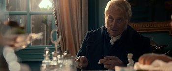Movie still from “Pride and Prejudice and Zombies” (2016), directed by Burr Steers – An older man sitting at a table with a glass of wine; Close Up shot, Over the shoulder angle