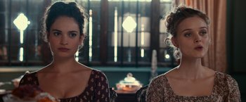 Movie still from “Pride and Prejudice and Zombies” (2016), directed by Burr Steers – Two women are standing next to each other in front of a window; Close Up shot, Over the shoulder angle
