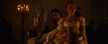 Movie still from “Pride and Prejudice and Zombies” (2016), directed by Burr Steers – A group of people sitting on top of a bed next to a statue; Medium shot, Over the shoulder angle