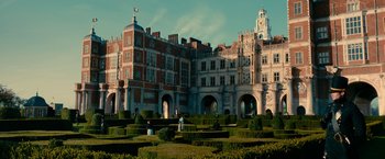 Movie still from “Pride and Prejudice and Zombies” (2016), directed by Burr Steers – People are standing in a garden in front of an old building; Extreme Wide shot, High angle