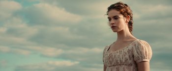 Movie still from “Pride and Prejudice and Zombies” (2016), directed by Burr Steers – A beautiful young woman standing in front of a cloudy sky; Close Up shot, Low angle