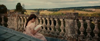 Movie still from “Pride and Prejudice and Zombies” (2016), directed by Burr Steers – A woman sitting on a ledge reading a book; Medium shot, High angle
