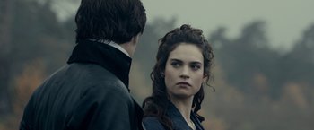 Movie still from “Pride and Prejudice and Zombies” (2016), directed by Burr Steers – A man and a woman standing next to each other in front of trees; Close Up shot, Over the shoulder angle