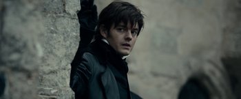 Movie still from “Pride and Prejudice and Zombies” (2016), directed by Burr Steers – A man in a black leather jacket standing next to a stone wall; Close Up shot, Over the shoulder angle