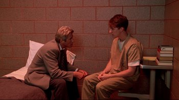 Movie still from “Primal Fear” (1996), directed by Gregory Hoblit – A man in a suit and a man in an orange shirt; Medium shot, Over the shoulder angle