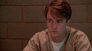 Movie still from “Primal Fear” (1996), directed by Gregory Hoblit – A young man sitting in front of a brick wall; Close Up shot, Low angle