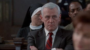 Movie still from “Primal Fear” (1996), directed by Gregory Hoblit – An older man in a suit and tie with his arms crossed; Close Up shot, Low angle