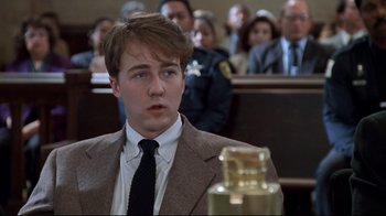 Movie still from “Primal Fear” (1996), directed by Gregory Hoblit – A man in a suit and tie in front of a group of people; Close Up shot, High angle