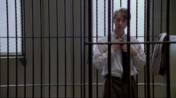 Movie still from “Primal Fear” (1996), directed by Gregory Hoblit – A man standing in front of a metal fence; Medium shot, Low angle