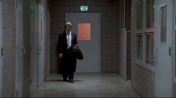 Movie still from “Primal Fear” (1996), directed by Gregory Hoblit – A man in a suit and tie walking in a hallway; Wide shot, Low angle