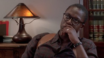 Movie still from “Primal Fear” (1996), directed by Gregory Hoblit – A man sitting in front of a table with his hand on his chin; Close Up shot, Over the shoulder angle