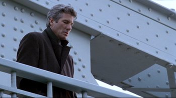 Movie still from “Primal Fear” (1996), directed by Gregory Hoblit – A man standing on top of a metal railing next to a building; Medium shot, Low angle