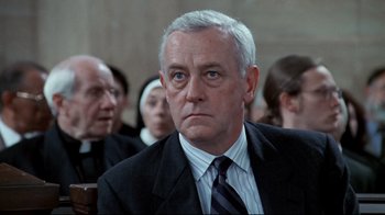 Movie still from “Primal Fear” (1996), directed by Gregory Hoblit – An older man wearing a suit and tie in front of a group of people; Close Up shot, Low angle