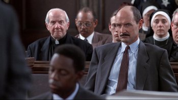Movie still from “Primal Fear” (1996), directed by Gregory Hoblit – A group of men sitting in front of each other in a court room; Medium shot, Low angle