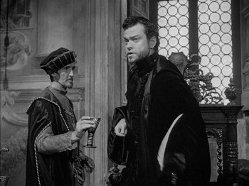 Movie still from “Prince of Foxes” (1949), directed by Henry King – Two men in medieval garb standing next to each other in front of a window; Medium shot, Over the shoulder angle