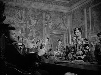 Movie still from “Prince of Foxes” (1949), directed by Henry King – A black and white photo of a group of people in a room; Wide shot, Over the shoulder angle