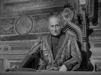 Movie still from “Prince of Foxes” (1949), directed by Henry King – An old man sitting in a chair wearing a robe; Medium shot, High angle