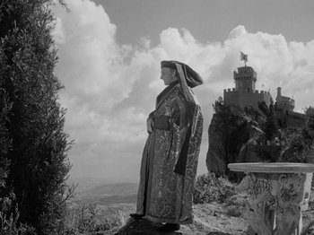 Movie still from “Prince of Foxes” (1949), directed by Henry King – A man standing on top of a hill wearing a robe and holding an umbrella; Wide shot, Low angle