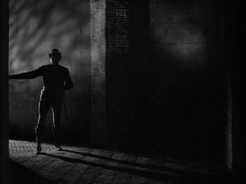 Movie still from “Prince of Foxes” (1949), directed by Henry King – A man standing in the dark holding a baseball bat; Wide shot, Low angle