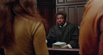 Movie still from “Prince of the City” (1981), directed by Sidney Lumet – A man in a robe is sitting in front of a woman in a courtroom; Medium shot, Over the shoulder angle