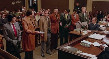 Movie still from “Prince of the City” (1981), directed by Sidney Lumet – A group of men standing in front of a table; Wide shot, High angle