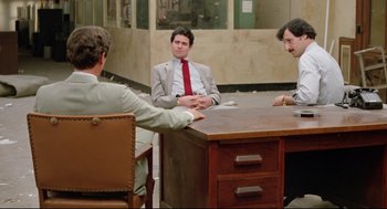 Movie still from “Prince of the City” (1981), directed by Sidney Lumet – A group of men sitting at a table talking to each other; Wide shot, High angle