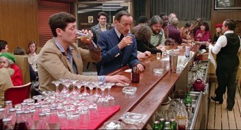 Movie still from “Prince of the City” (1981), directed by Sidney Lumet – A group of people sitting at a long bar; Wide shot, Over the shoulder angle