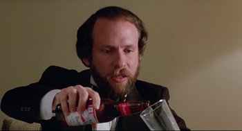 Movie still from “Prince of the City” (1981), directed by Sidney Lumet – A man in a black suit is pouring beer into a can; Close Up shot, High angle