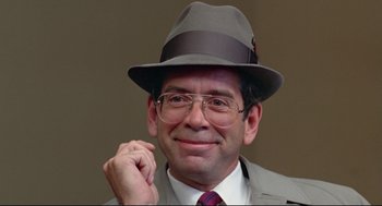 Movie still from “Prince of the City” (1981), directed by Sidney Lumet – A person wearing a hat and glasses; Close Up shot, Over the shoulder angle