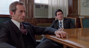 Movie still from “Prince of the City” (1981), directed by Sidney Lumet – Two men sitting at a table in a courtroom; Medium shot, Over the shoulder angle