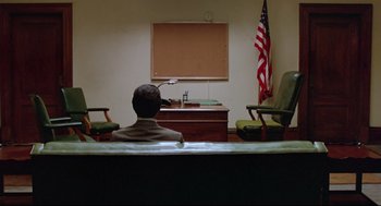 Movie still from “Prince of the City” (1981), directed by Sidney Lumet – A man sitting in front of an american flag in a courtroom; Extreme Wide shot, High angle