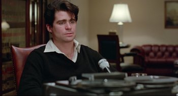 Movie still from “Prince of the City” (1981), directed by Sidney Lumet – A man sitting in front of a microphone in a room; Close Up shot, Over the shoulder angle