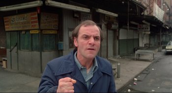 Movie still from “Prince of the City” (1981), directed by Sidney Lumet – A man in a blue jacket standing in front of a building; Close Up shot, Low angle