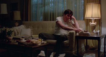 Movie still from “Prince of the City” (1981), directed by Sidney Lumet – A man sitting on top of a couch next to a coffee table; Medium shot, Low angle