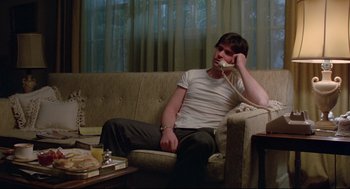 Movie still from “Prince of the City” (1981), directed by Sidney Lumet – A man sitting on a couch talking on the phone; Medium shot, Low angle