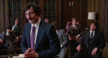 Movie still from “Prince of the City” (1981), directed by Sidney Lumet – A group of men in suits and ties sitting in a room; Medium shot, Over the shoulder angle