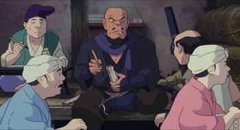 Movie still from “Princess Mononoke” (1997), directed by Hayao Miyazaki – An old man sitting on the ground with a pen in his mouth; Medium shot, High angle