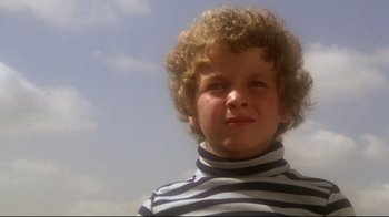 Movie still from “Prom Night” (1980), directed by Paul Lynch – A young boy with curly hair wearing a striped shirt; Close Up shot, Low angle